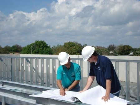 Two ANC Roofing roofers looking over plans on a flat roof